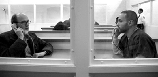 Walter and Tarek speaking over phones at the detention center.